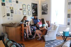 学生 playing guitars together in a dorm room